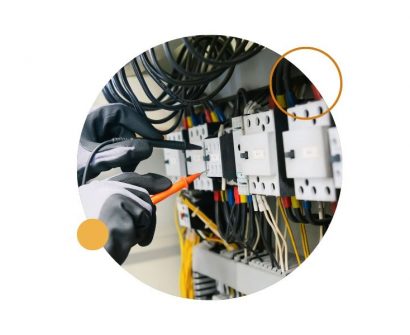Electricista con guantes midiendo un cuadro eléctrico, imagen sobre estudiar electricidad profesional.