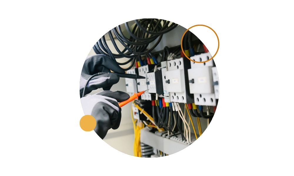 Electricista con guantes midiendo un cuadro eléctrico, imagen sobre estudiar electricidad profesional.